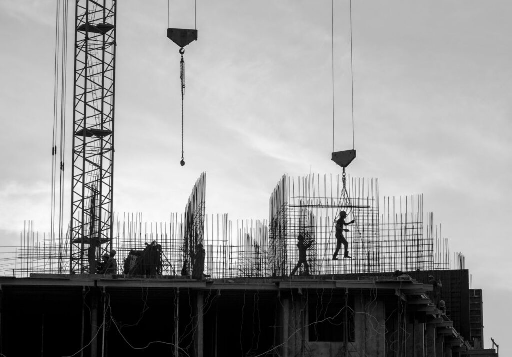 Silhouette of workers on a construction site with cranes and scaffolding in Saint Petersburg.